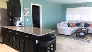 Una cocina moderna con gabinetes oscuros, encimera de granito y una isla integrada con taburetes de bar.