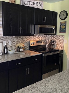 A modern kitchen with dark cabinetry, stainless steel appliances, and a tiled backsplash. - New listing 3bd/2bt Sleeps 8 "Sunset Paradise Villa" on canal Big Pine Key (Big Pine Key)