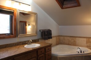 Een bad/douchecombinatie, een bubbelbad, een haardroger, handdoeken