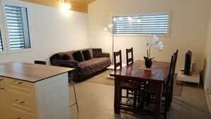A modern kitchen with a wooden countertop, a dining table with chairs, a sofa, and a potted orchid. - Appartement Individuel (Châtel-Saint-Denis)