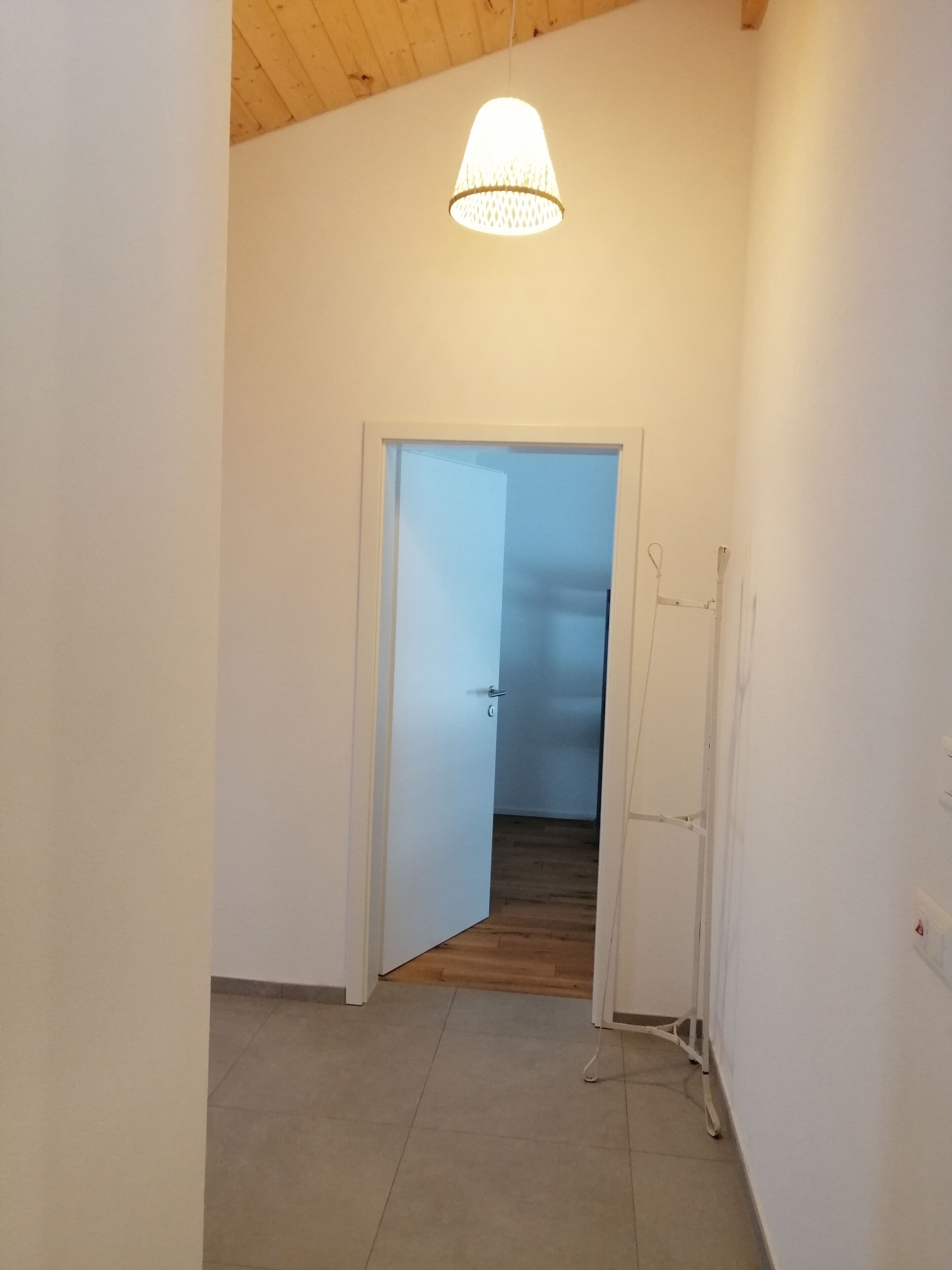 A hallway with a white door leading to a room with a wooden floor.