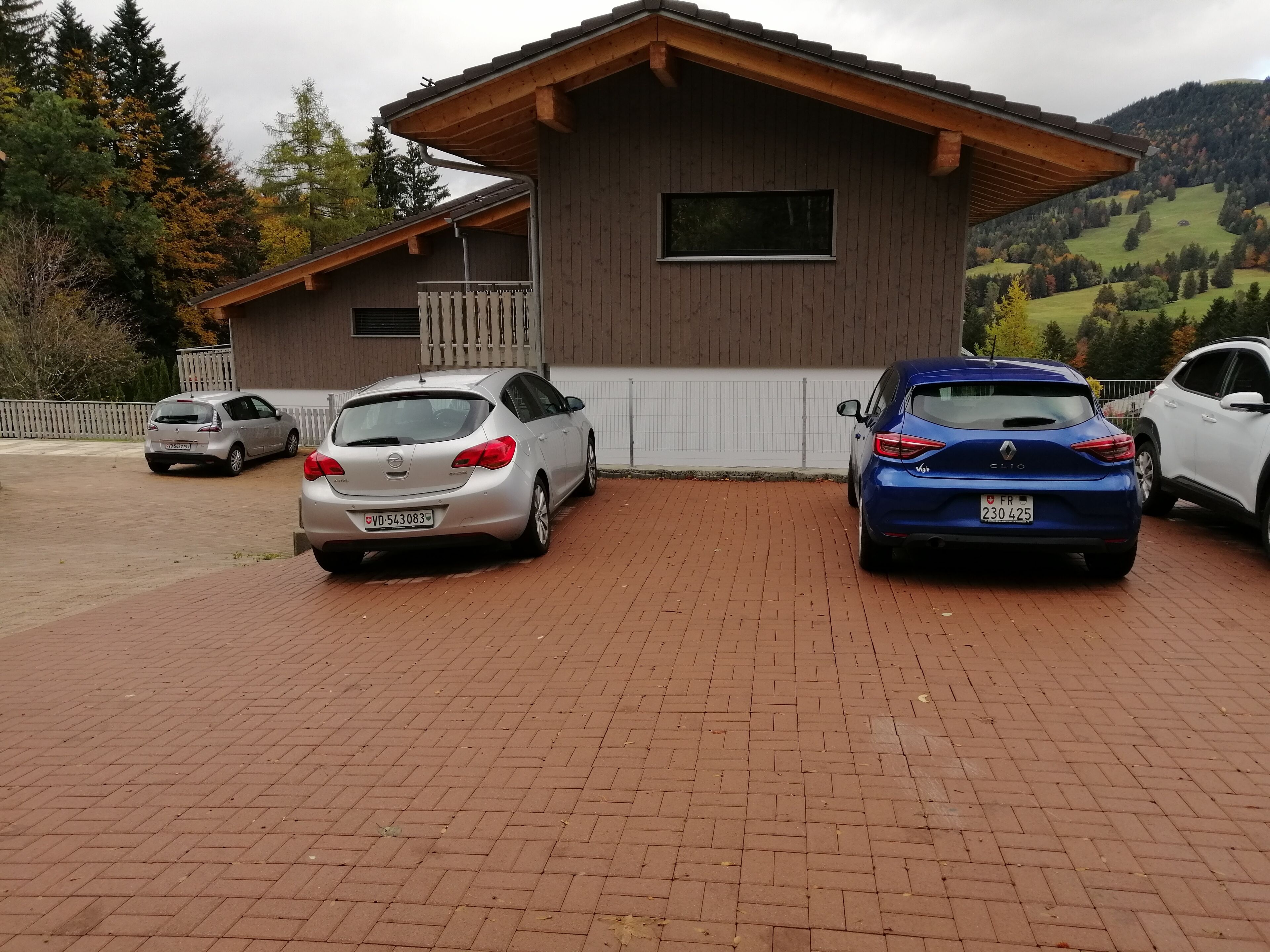 Un edificio con fachada de madera y camino de ladrillo. Hay dos coches estacionados al frente.