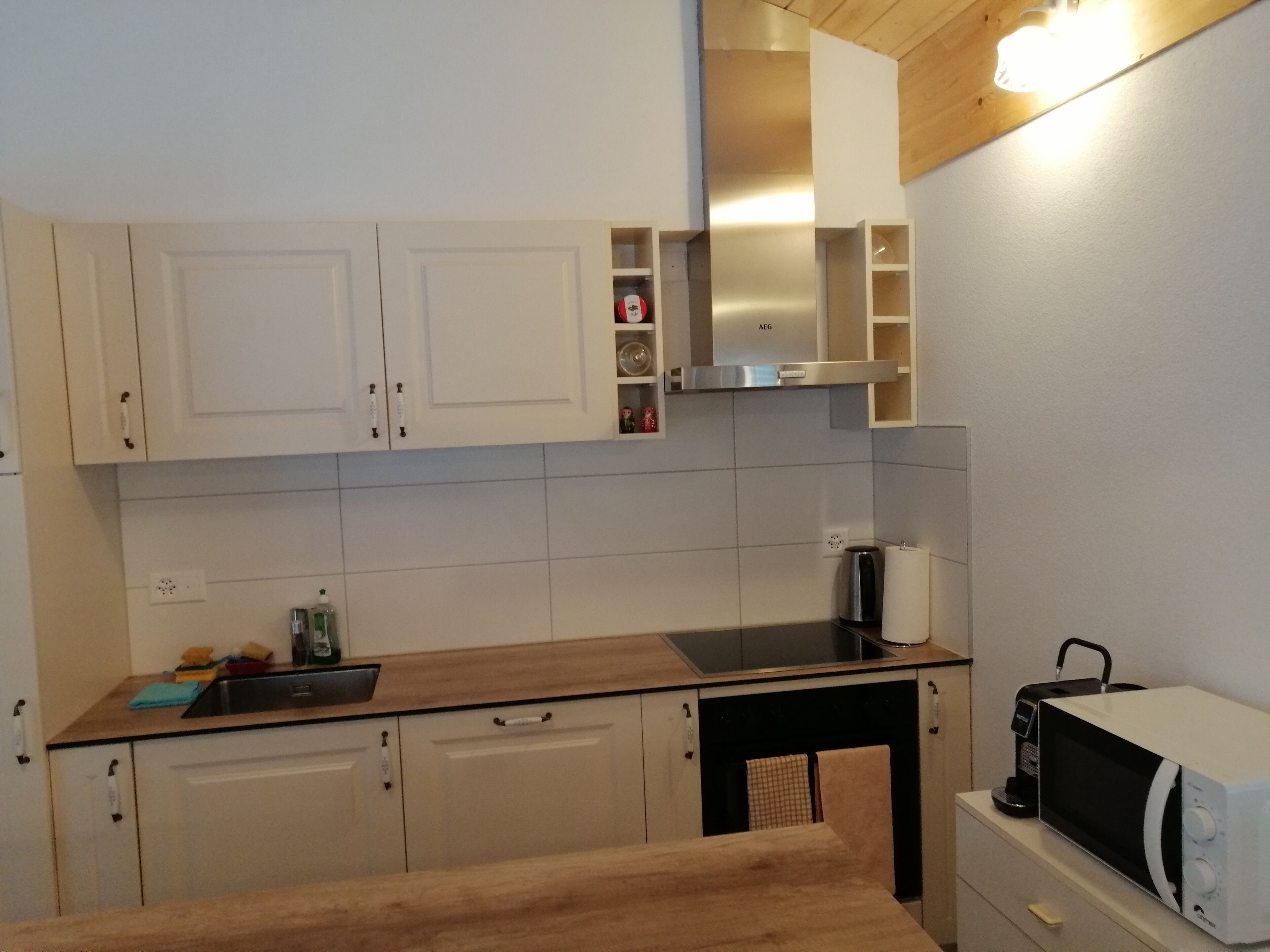 Eine Küche mit weißen Schränken, einer Holz Arbeitsplatte, einer Mikrowelle und einer Kaffeemaschine.