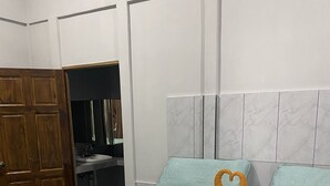 Un dormitorio con cama, un armario de madera y un baño visible a través de una puerta abierta.