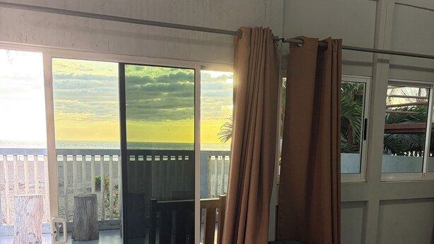 Una habitación con puerta corrediza de vidrio que da a un balcón con vista a la playa.