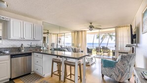 Una cocina moderna con una isla central, taburetes de bar y vista al océano a través de amplios ventanales.