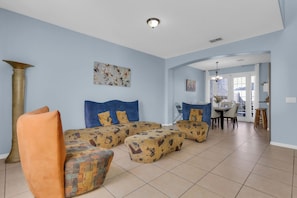 Uma sala de estar com sofá seccional, uma mesa de centro e um espaço de jantar com mesa e cadeiras.