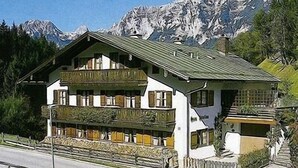 Ein traditionelles Chalet mit Balkon, vor einer Kulisse schneebedeckter Berge.