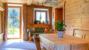 A cozy room with a wooden interior, a dining table with chairs, a sofa, and a window with curtains. - Ferienwohnung , Terr., Küche, 2 Schlaf- u. 1 Wohn-/schlafz., max 4 P (Ruhpolding)