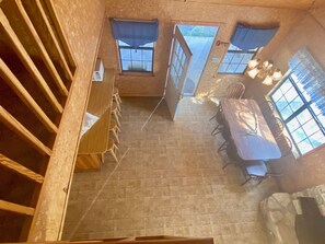A room with a dining table and chairs, a window with curtains, and a door leading outside. - Float 2 Cabin! Comanche Crossing, Private River Access, Near Music Venues! (Concan)