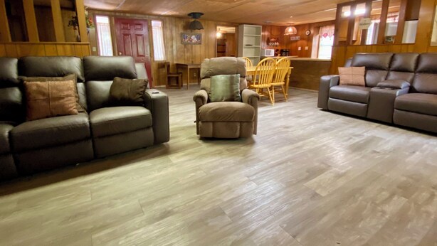Un salon chaleureux avec un canapé en cuir marron, un fauteuil assorti et une table à manger en bois avec des chaises.
