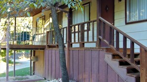 Un bâtiment à deux étages avec un escalier en bois menant à un porche.
