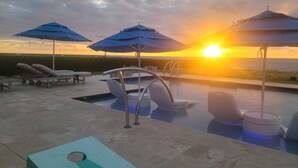 A pool area with lounge chairs, umbrellas, and a view of the sunset. - Oceanfront Resort-Style Home3br, 2Ba - Private Pool & Island car included (Cockburn Town)