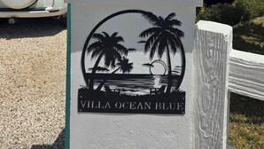 A sign with a lighthouse and palm trees, labeled "Villa Ocean Blue". - Oceanfront Resort-Style Home3br, 2Ba - Private Pool & Island car included (Cockburn Town)