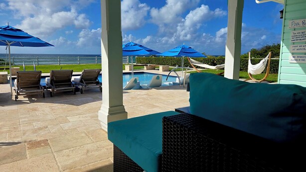 A pool area with lounge chairs, umbrellas, and a view of the ocean. - Oceanfront Resort-Style Home3br, 2Ba - Private Pool & Island car included (Cockburn Town)