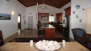 A spacious kitchen with wooden cabinets, a central island, and a dining area with a table set for two. - Oceanfront Resort-Style Home3br, 2Ba - Private Pool & Island car included (Cockburn Town)