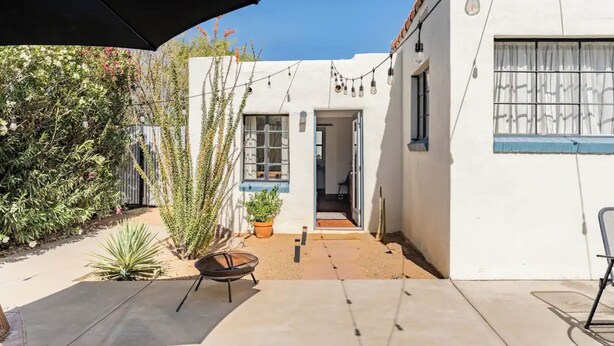A courtyard with a patio, a black umbrella, and string lights.