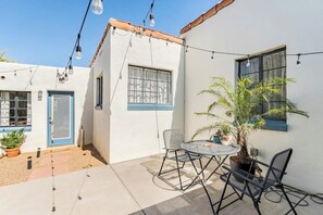 A patio area with a table and chairs, a potted plant, and string lights. - Spanish Bungalow Casita With Tucson Charm (Tucson)