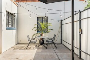 A patio with a round table and chairs, a potted plant, and string lights. - Spanish Bungalow Casita With Tucson Charm (Tucson)