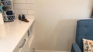 A kitchen with white cabinets, a blue sofa, and a pet feeding area. - In Town. Pet Friendly. Quiet Neighborhood. Queen Bed. Perfect Getaway! (Fredericksburg)