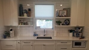 A modern kitchen with white cabinetry, a built-in sink, a microwave, and various kitchen accessories. - In Town. Pet Friendly. Quiet Neighborhood. Queen Bed. Perfect Getaway! (Fredericksburg)