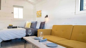 Ein Zimmer mit einem Bett, einer Couch, einem Tisch mit Tellern und Gläsern sowie einem Fenster.