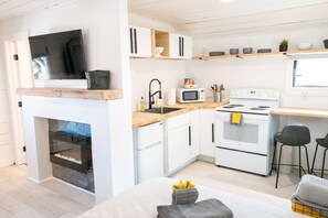 A modern kitchen with white cabinetry, a built-in microwave, a stove, and a fireplace.