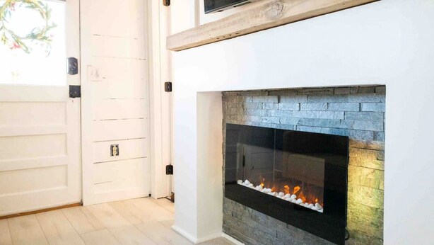 Ein modernes Interieur mit Kamin, weißen Wänden und einer Holzbalkendecke.