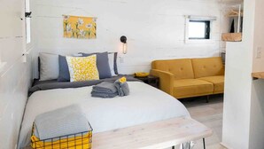 Ein Schlafzimmer mit einem Bett, einer Couch, einer Wandleuchte und einem Fenster.