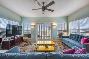 A living room with a television, sofa, coffee table, and a ceiling fan.