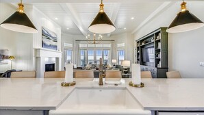 A spacious kitchen with a central island, pendant lighting, and a view to the dining area. - THE NEW PREMIER BEACHFRONT PLANTATION HOME, LAZY GATOR, IS FINALLY COMPLETE! (St. George Island)