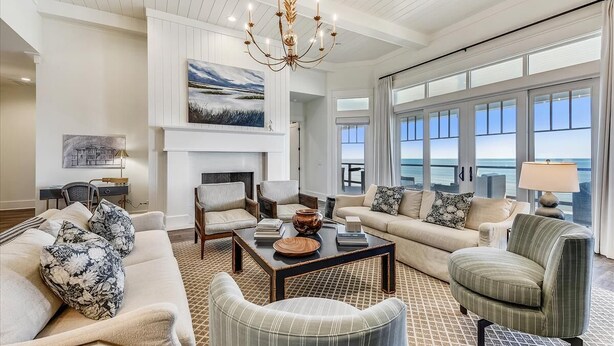 A spacious living room with a fireplace, large windows, and a view of the ocean. - THE NEW PREMIER BEACHFRONT PLANTATION HOME, LAZY GATOR, IS FINALLY COMPLETE! (St. George Island)