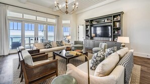 A spacious living room with a large television, comfortable seating, and a view of the ocean. - THE NEW PREMIER BEACHFRONT PLANTATION HOME, LAZY GATOR, IS FINALLY COMPLETE! (St. George Island)