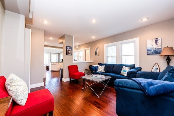 Un salon moderne avec un canapé bleu, un fauteuil rouge et une table basse.