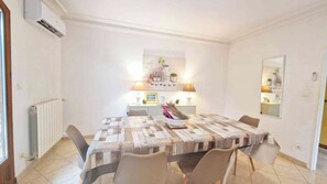 Uma sala de jantar com mesa posta para quatro pessoas, um radiador e um ar condicionado fixado na parede.