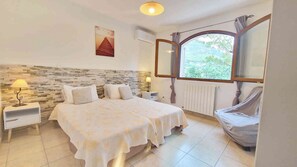 A bedroom with two beds, a stone wall, a window with a view, and a radiator. - BEAUTIFUL ACCOMODATION ON AGRITOURISME NEAR NICE ANTIBES CANNES  (Le Bar-sur-Loup)