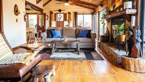 A rustic interior with a wooden ceiling, a sofa with blue cushions, a coffee table, and a fireplace with bear sculptures. - Black Bear Lodge at gorgeous Lake Jocassee (Salem)