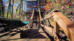 A wooden staircase leading to a wooden deck with a hammock and a wooden railing. - Black Bear Lodge at gorgeous Lake Jocassee (Salem)
