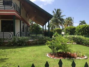 Relax in a serene outdoor space surrounded by lush vegetation and a covered walkway leading to a balcony.
