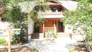 Eine zweistöckige Holzhütte mit Veranda und einem kleinen Garten.