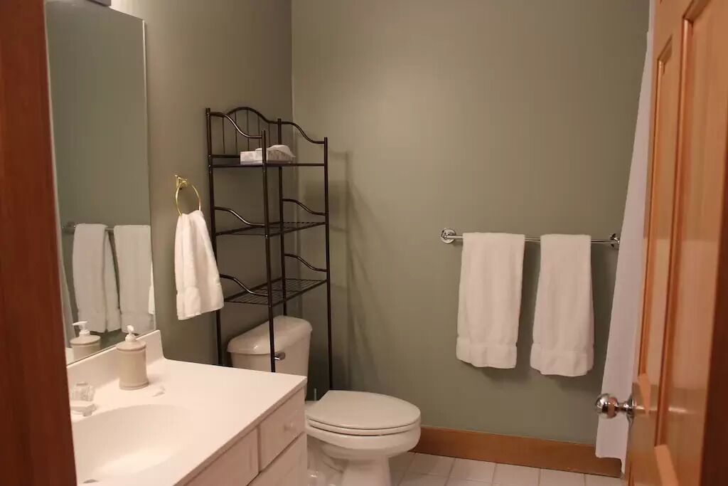 Un bagno con lavandino bianco, un water, uno specchio e un porta asciugamani.