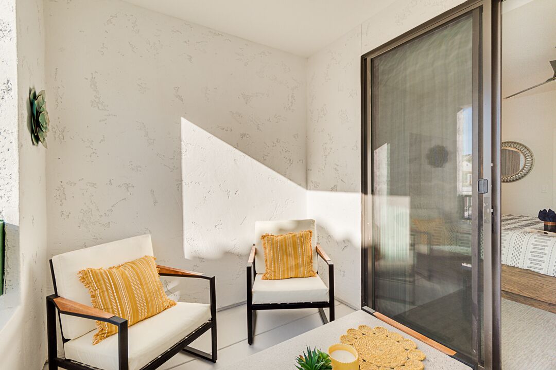 A room with two chairs, a small table, and a sliding glass door leading to another room.