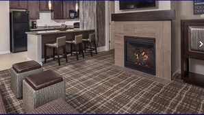 A modern living room with a sofa, ottomans, a fireplace, and a kitchen area with a bar.