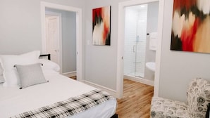 Une chambre à coucher avec un lit, une chaise et une salle de bain avec douche.