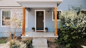Une maison avec un porche, une porte et un petit jardin.