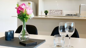 A dining table with a vase of flowers, two wine glasses, and a black notebook.