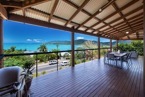A covered outdoor area with a view of the ocean, a grill, and seating. - 49 On Airlie - Airlie Beach (Airlie Beach)