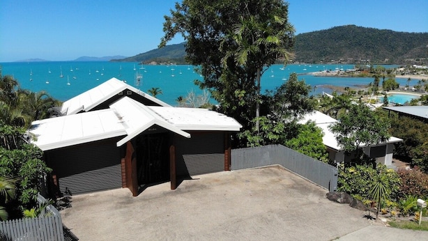 Un immobile residenziale con garage, vialetto e vista su una baia con barche.