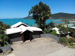 A residential property with a garage, a driveway, and a view of a bay with boats. - 49 On Airlie - Airlie Beach (Airlie Beach)