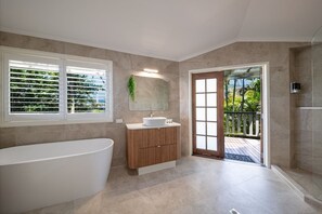 A modern bathroom with a freestanding bathtub, a wooden vanity, and a glass door leading to an outdoor area. - 49 On Airlie - Airlie Beach (Airlie Beach)